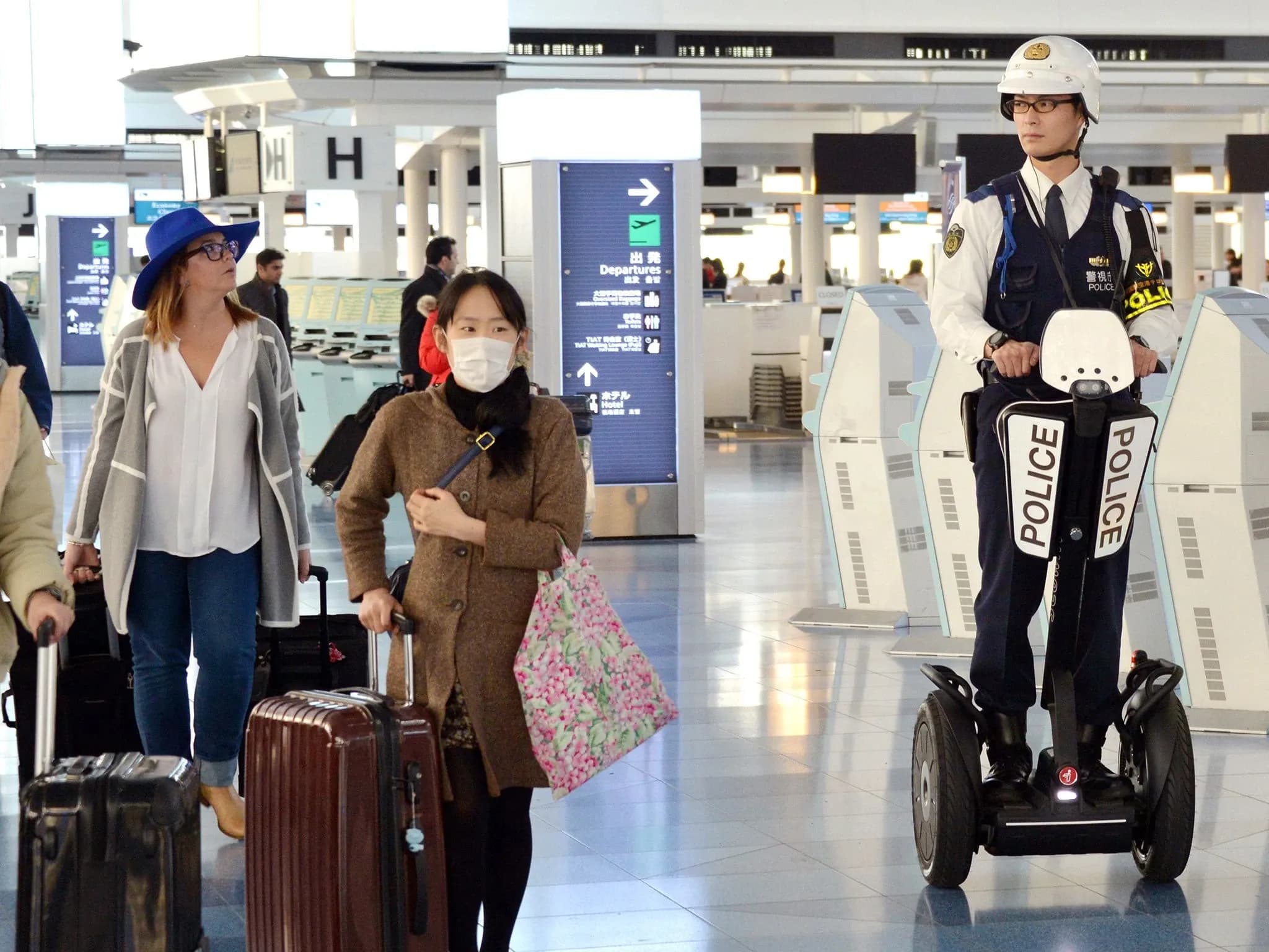 Полицейский на Segway проезжает мимо пассажиров в аэропорту.