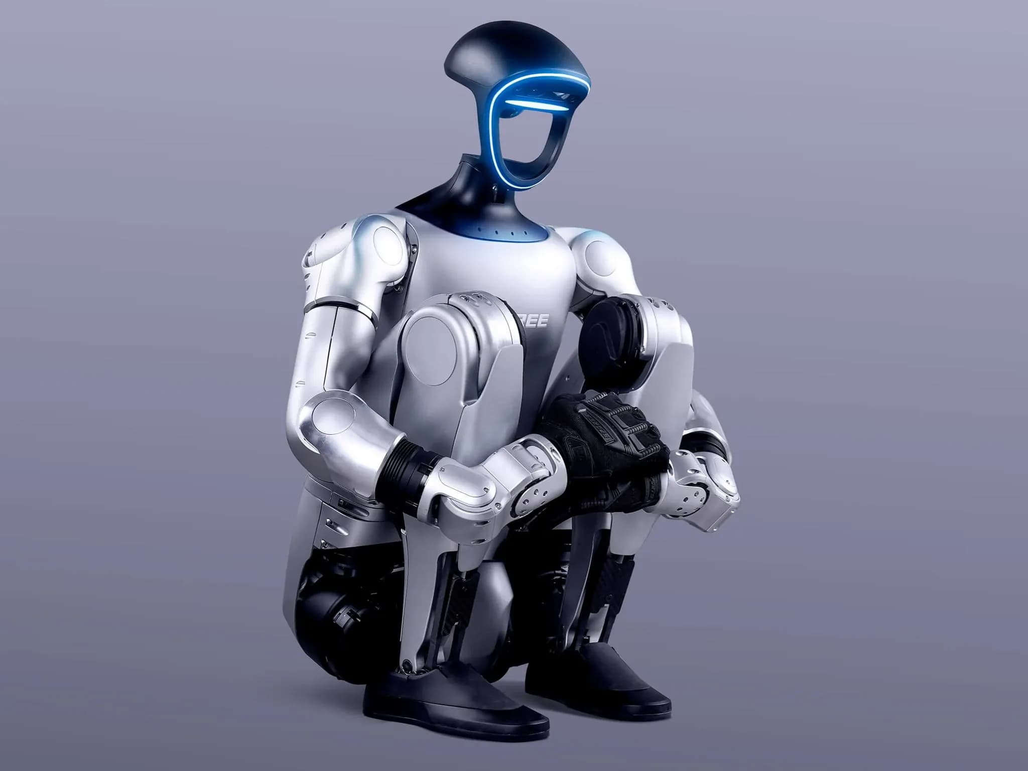Двуногий гуманоидный робот G1 от Unitree Robotics приседает до упора — корпус прижат к ногам, руки обхватывают голени.