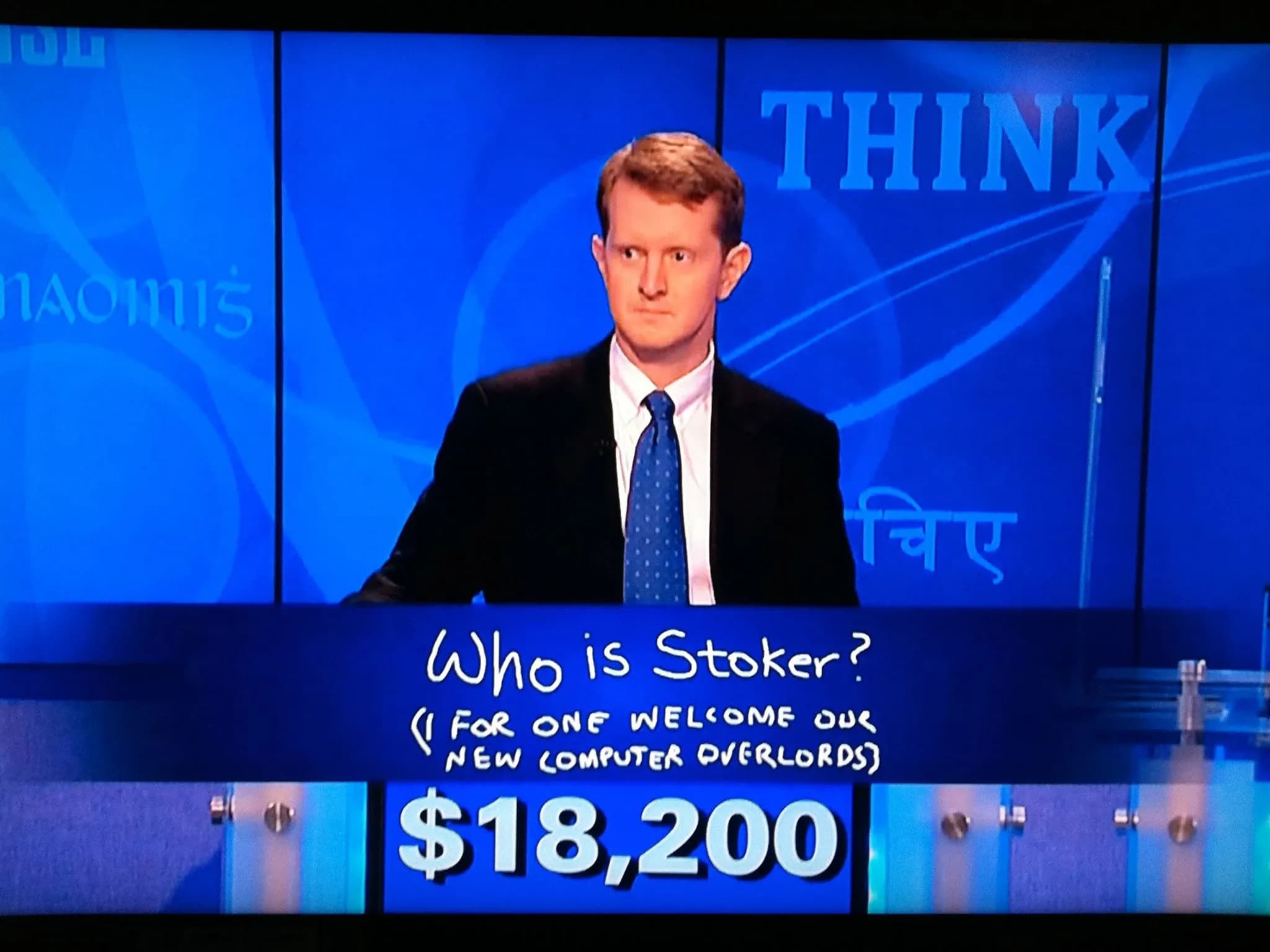 Любопытный мужчина в костюме играет в Jeopardy! У него $18 200, и он написал «Кто такой Stocker? (Я, со своей стороны, приветствую наших новых компьютерных повелителей)».