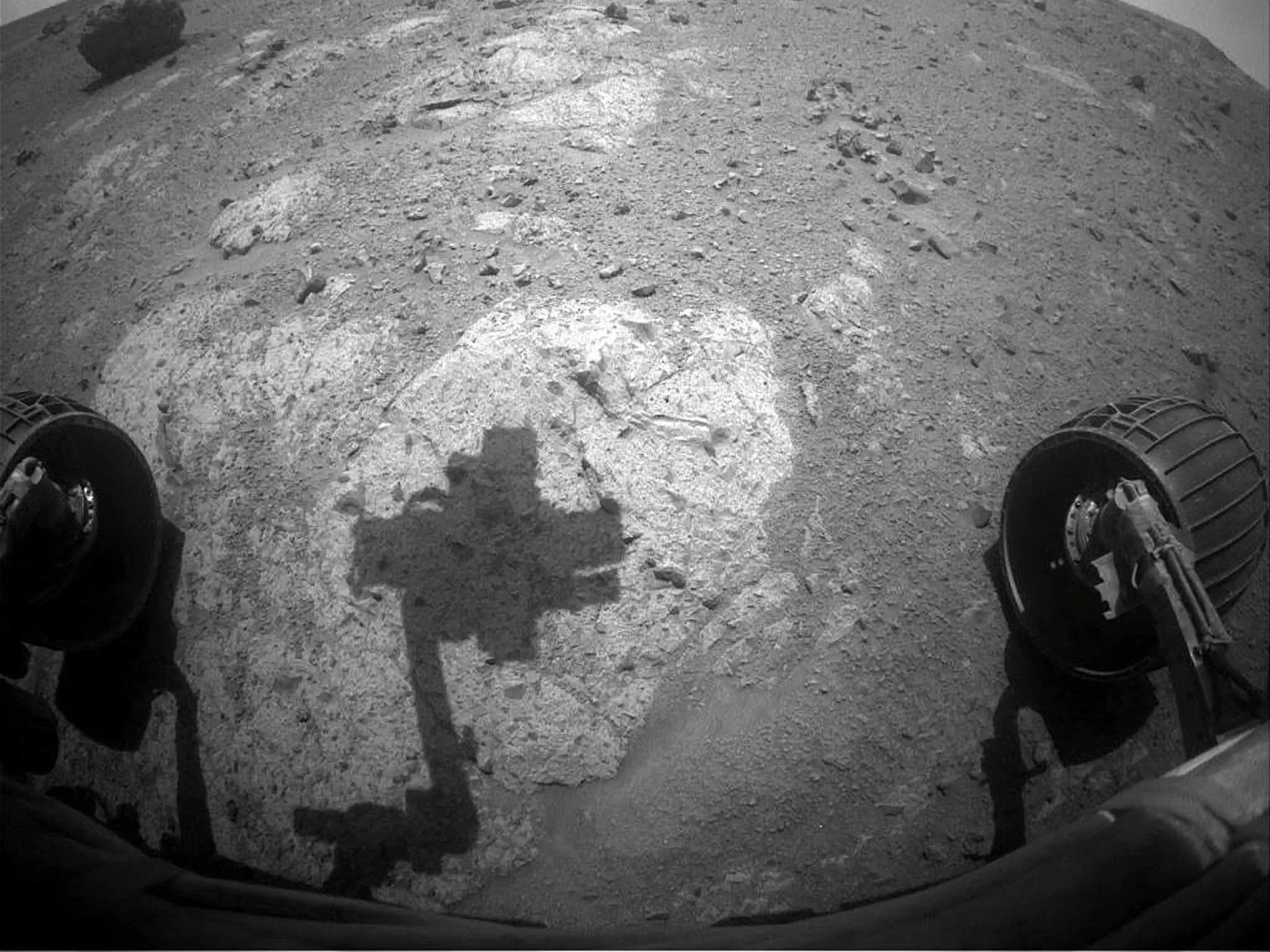 Чёрно-белый снимок, сделанный Opportunity: видны два его колеса и тень от головы.