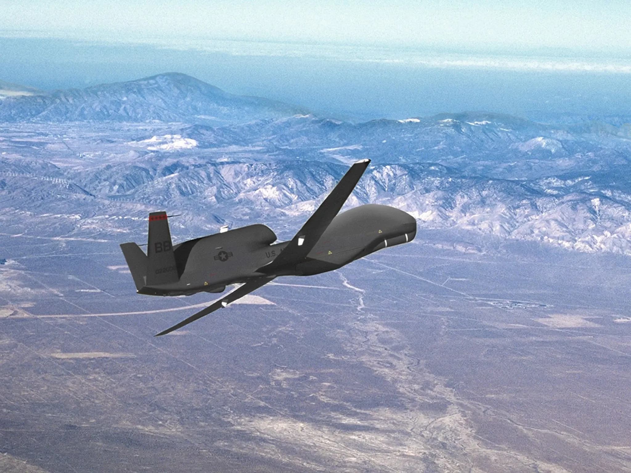 Вид на беспилотник Global Hawk UAV, летящий над пустынным ландшафтом.